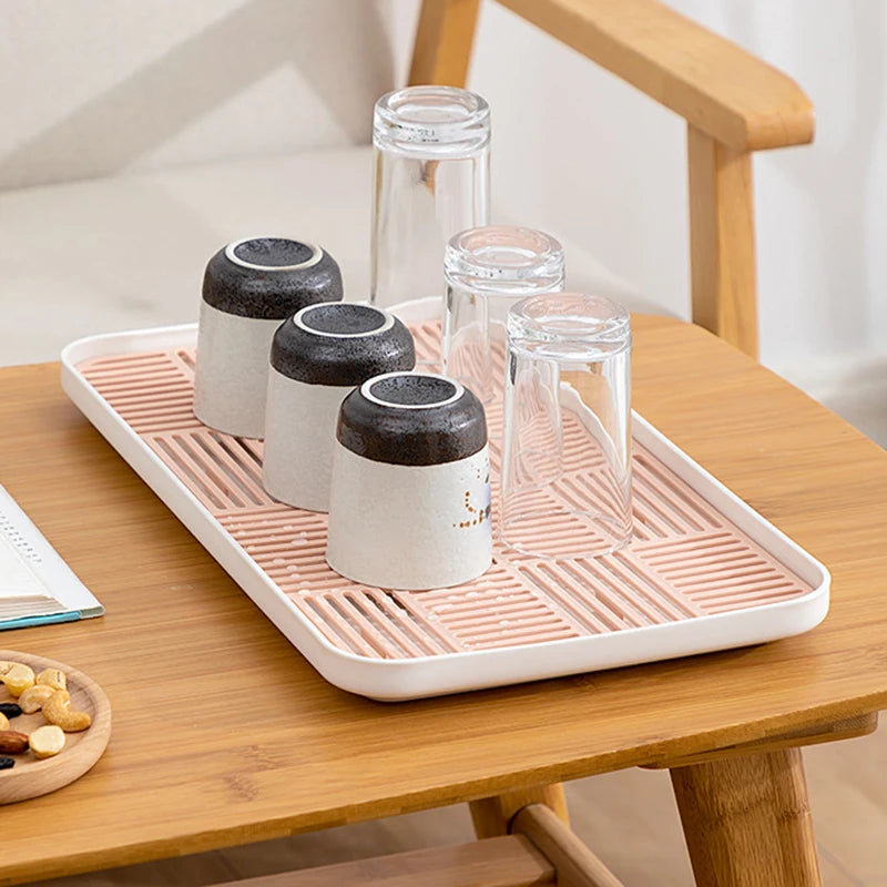 Égouttoir vaisselle plastique rose sur table avec verres