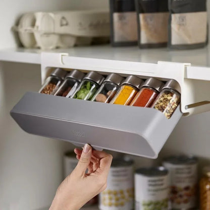 Étagère à épices coulissante sans perçage dans une armoire blanche avec condiments variés - main humaine tenant l'étagère